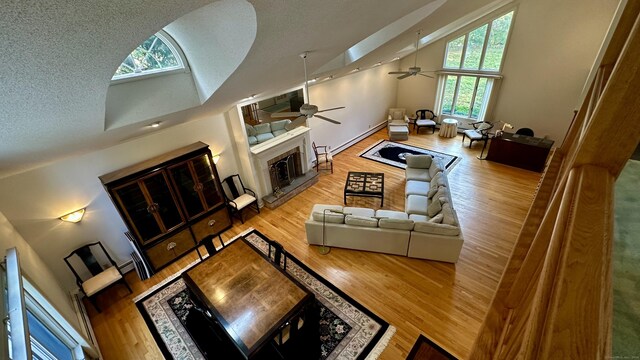 162 Pequot Trl, Stonington, CT 06379 - living room featuring a fireplace with raised hearth, ceiling fan, high vaulted ceiling, wood finished floors, and a textured ceiling