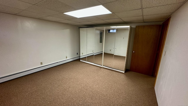 finished basement featuring electric panel, a paneled ceiling, and a baseboard radiator