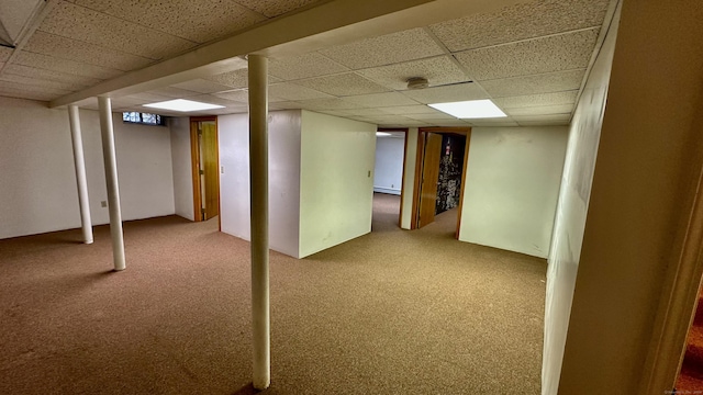 finished basement featuring a paneled ceiling, a baseboard heating unit, and carpet floors