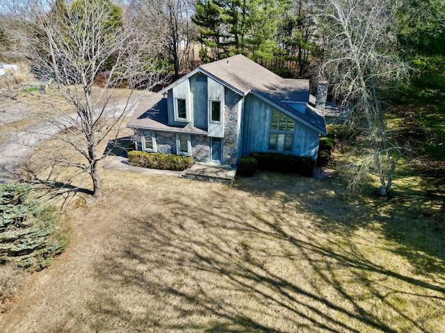 exterior space with stone siding and a lawn