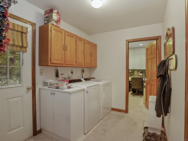 clothes washing area with washer and dryer, cabinets, and light tile patterned floors