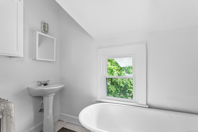 bathroom with a wealth of natural light, tile patterned flooring, and vaulted ceiling