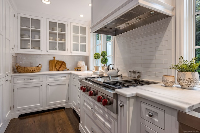 kitchen with tasteful backsplash, white cabinets, premium range hood, dark hardwood / wood-style floors, and stainless steel gas cooktop