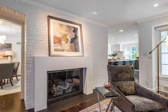 living area featuring brick wall, crown molding, and dark hardwood / wood-style floors