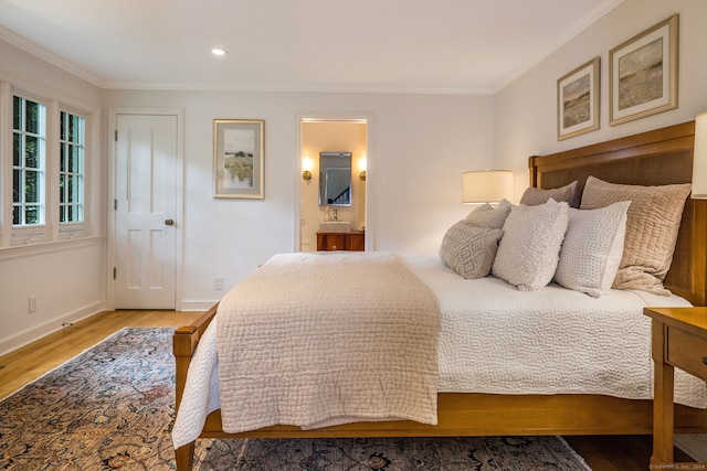 bedroom featuring ornamental molding, ensuite bath, and light wood-type flooring