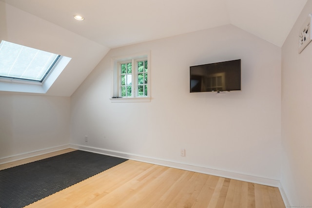 bonus room featuring wood-type flooring and vaulted ceiling with skylight