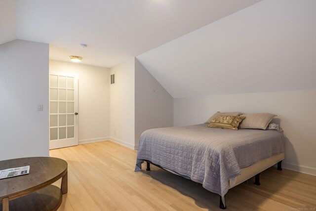 bedroom featuring light hardwood / wood-style floors and vaulted ceiling