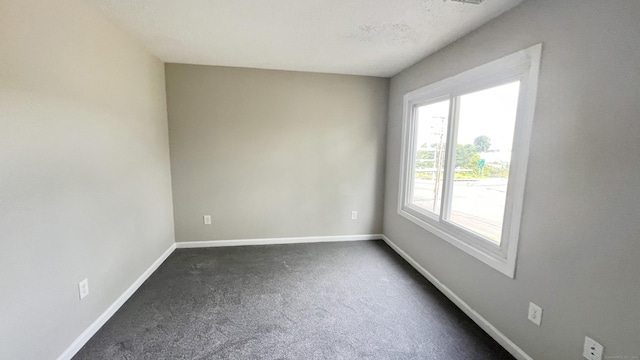 spare room featuring dark colored carpet