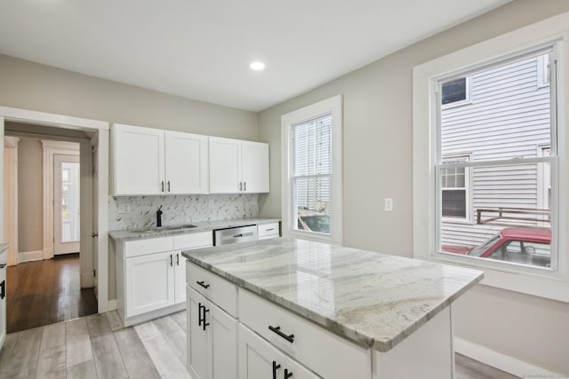 kitchen featuring decorative backsplash, light hardwood / wood-style flooring, stainless steel dishwasher, and a center island