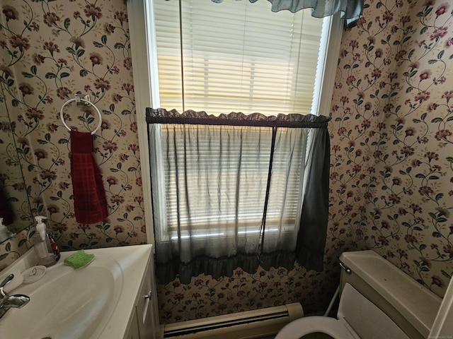 bathroom featuring plenty of natural light, a baseboard heating unit, vanity, and toilet