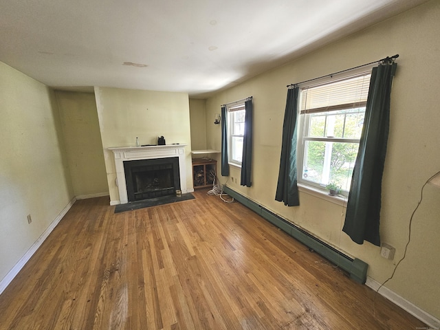 unfurnished living room with hardwood / wood-style flooring and a baseboard heating unit