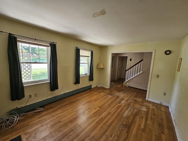 unfurnished room with a baseboard heating unit and wood-type flooring