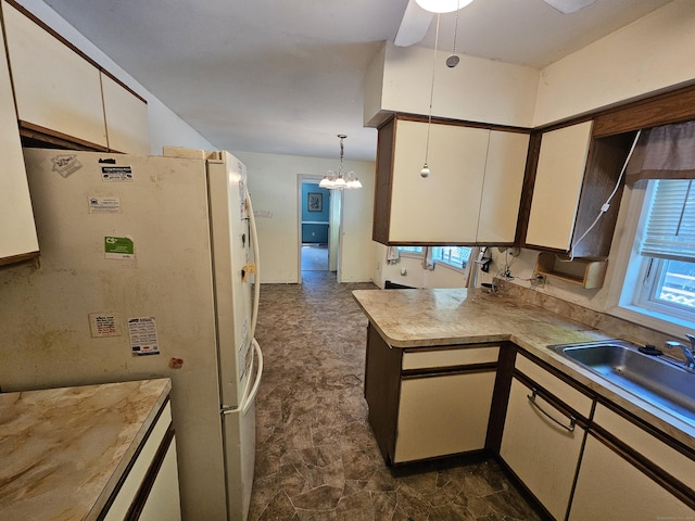 kitchen with pendant lighting, white cabinetry, white fridge, sink, and kitchen peninsula