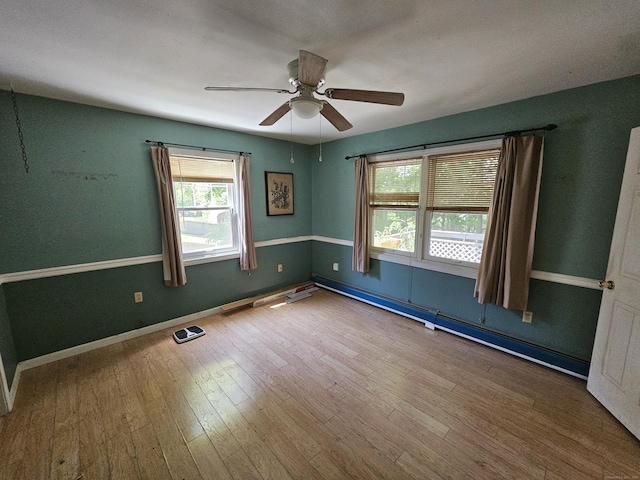 empty room with ceiling fan, a baseboard radiator, and wood-type flooring