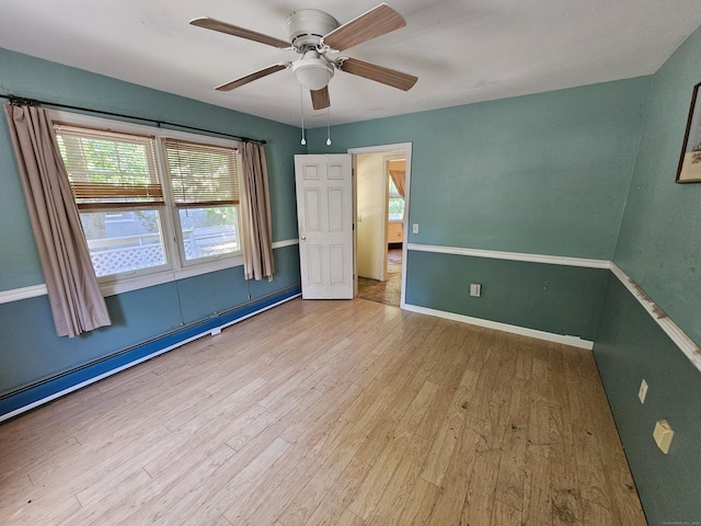 unfurnished bedroom featuring ceiling fan, a baseboard radiator, and light hardwood / wood-style flooring