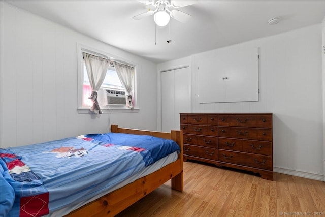 bedroom with ceiling fan, light hardwood / wood-style floors, cooling unit, and a closet