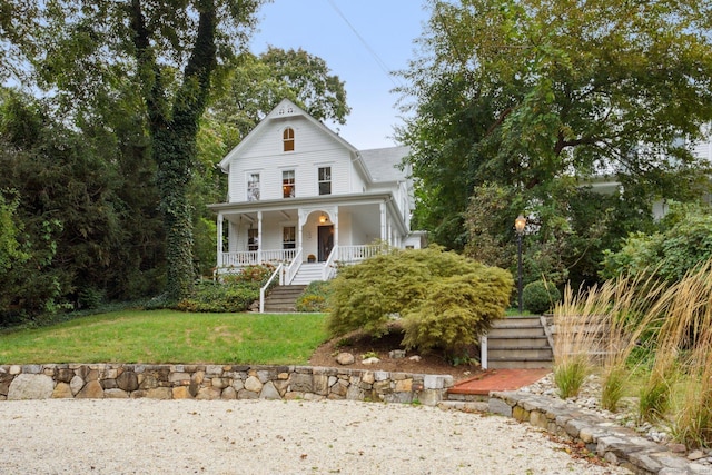victorian-style house featuring stairs, covered porch, and a front yard
