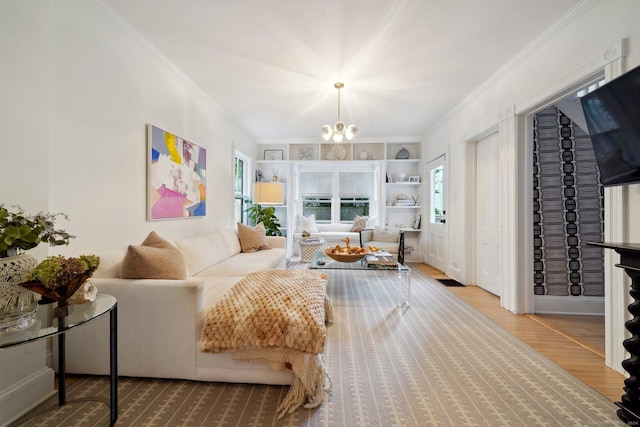living room with crown molding, wood finished floors, a chandelier, and built in features