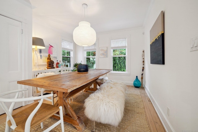 dining area with light wood-type flooring, crown molding, and baseboards