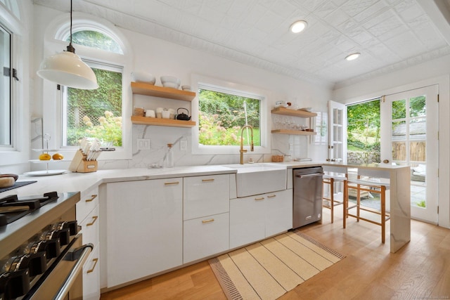 kitchen featuring open shelves, a sink, appliances with stainless steel finishes, light wood-type flooring, and recessed lighting