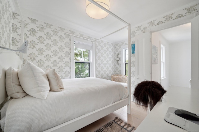 bedroom with wood finished floors and wallpapered walls