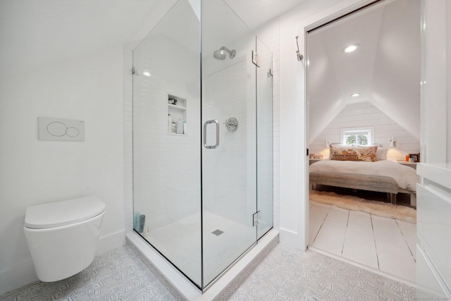 ensuite bathroom featuring toilet, lofted ceiling, a shower stall, and tile patterned flooring