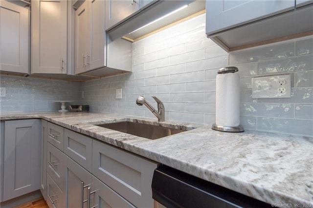 kitchen featuring light stone countertops, sink, gray cabinetry, and backsplash