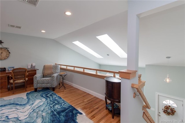 living area featuring hardwood / wood-style floors and vaulted ceiling with skylight