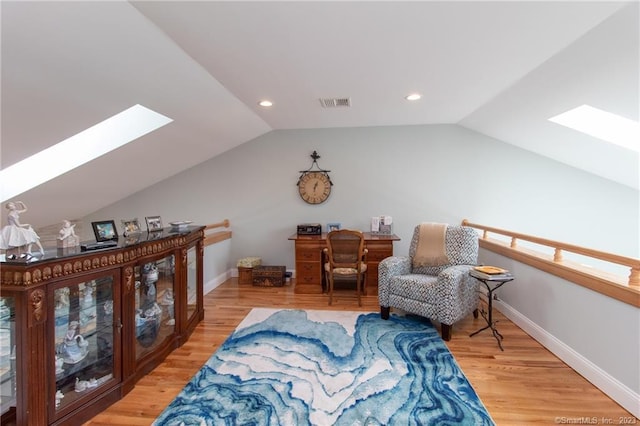 living area with hardwood / wood-style flooring and vaulted ceiling with skylight