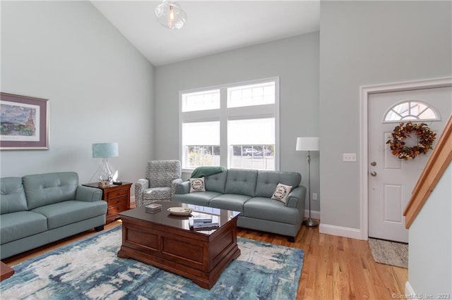 living room featuring high vaulted ceiling and light hardwood / wood-style flooring