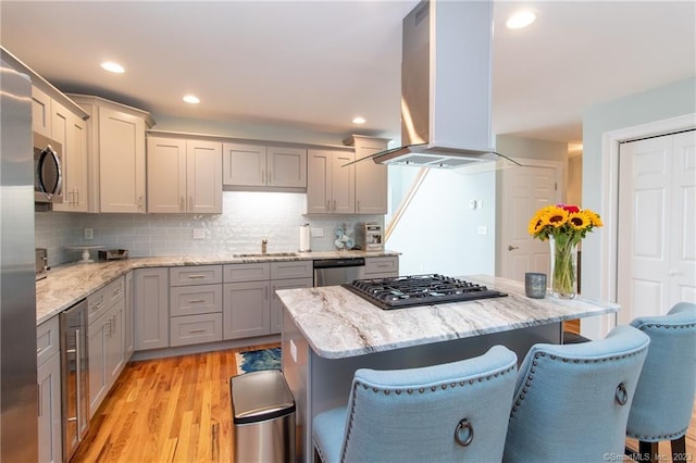 kitchen with sink, a breakfast bar area, light hardwood / wood-style flooring, appliances with stainless steel finishes, and island exhaust hood