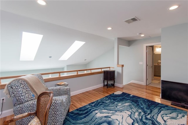 sitting room featuring hardwood / wood-style flooring and lofted ceiling with skylight