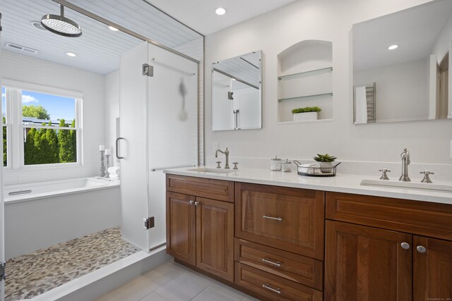 bathroom featuring tile patterned flooring, shower with separate bathtub, and double sink vanity