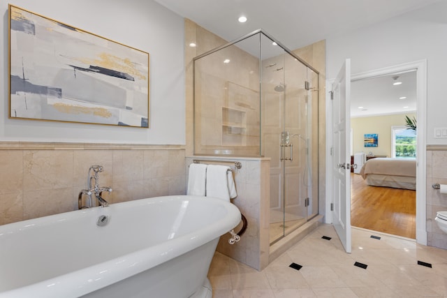 bathroom featuring plus walk in shower, toilet, hardwood / wood-style flooring, and tile walls