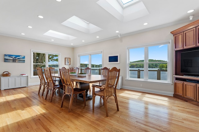 dining space with a skylight, crown molding, and light hardwood / wood-style floors