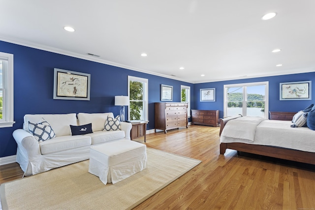 bedroom with ornamental molding, multiple windows, and light hardwood / wood-style flooring