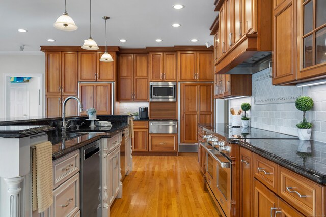 kitchen with backsplash, hanging light fixtures, light wood-type flooring, and built in appliances