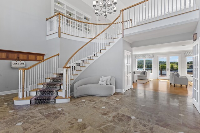 staircase with an inviting chandelier, french doors, wood-type flooring, and a towering ceiling