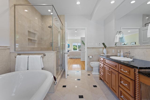 full bathroom with vanity, shower with separate bathtub, tile walls, and toilet