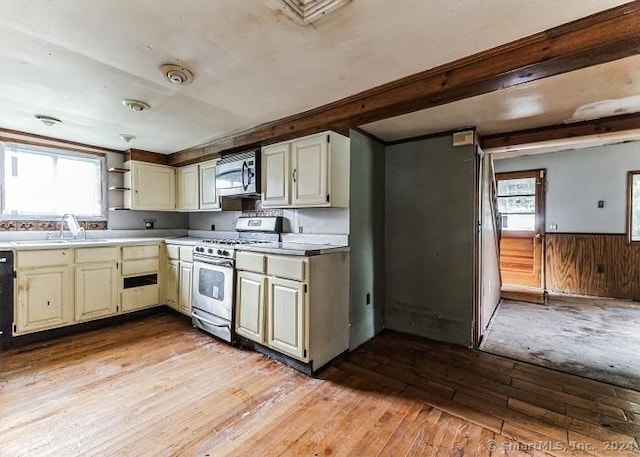 kitchen featuring light wood-type flooring, stainless steel appliances, wood walls, and plenty of natural light