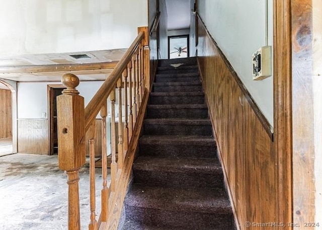 stairway featuring wooden walls