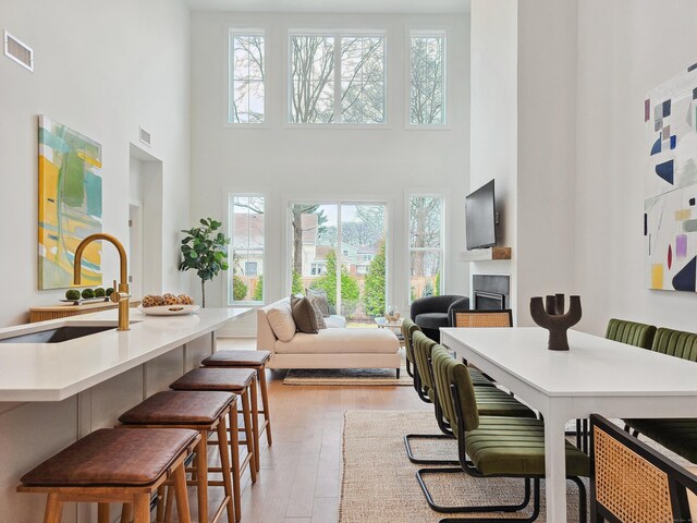 interior space with a high ceiling, light wood-style flooring, a fireplace, and visible vents