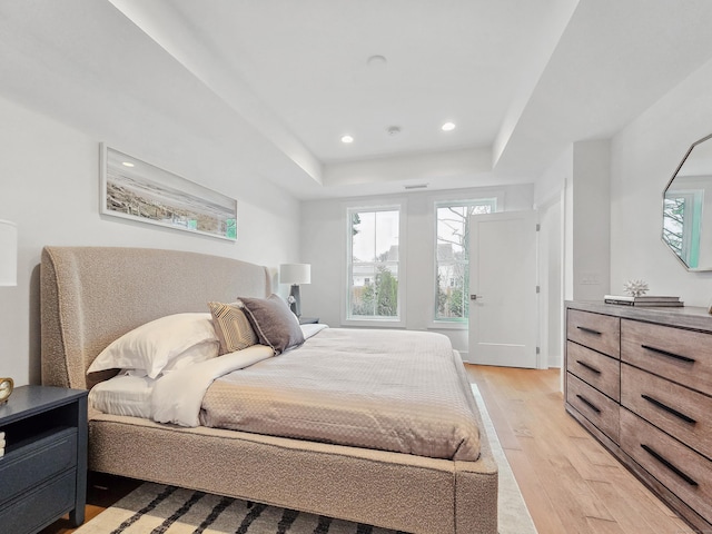 bedroom featuring light wood-type flooring, a tray ceiling, and recessed lighting