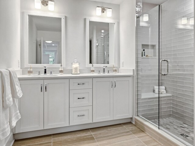 full bathroom with a sink, double vanity, and a shower stall