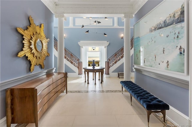 tiled foyer entrance with ornamental molding and ornate columns