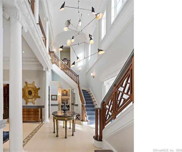 foyer entrance featuring a high ceiling, ornamental molding, a notable chandelier, and light tile patterned floors