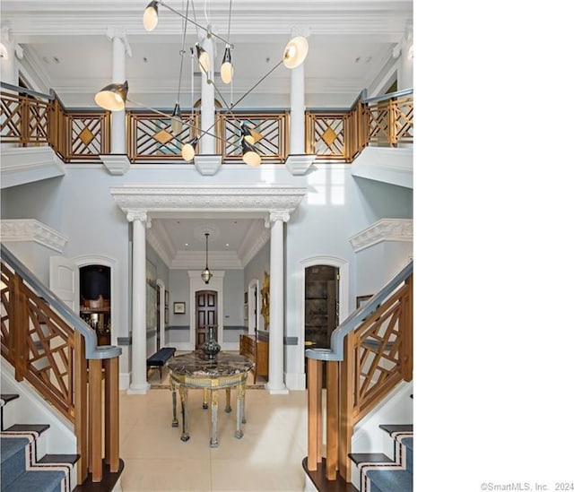 tiled foyer entrance featuring ornamental molding, ornate columns, and a towering ceiling