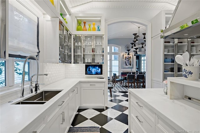 kitchen featuring sink, white cabinetry, light tile patterned floors, and backsplash