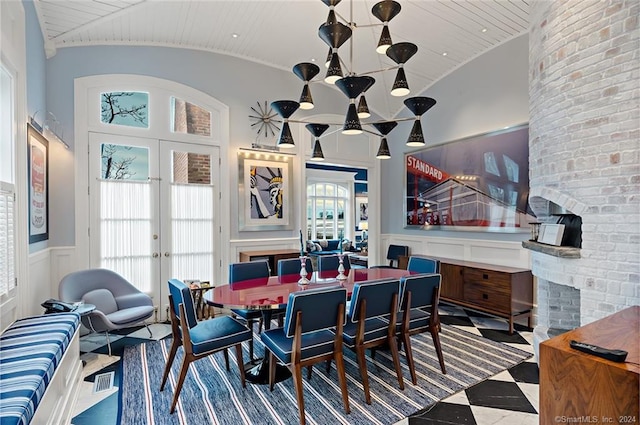 dining area with high vaulted ceiling, brick wall, and tile patterned floors