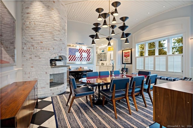 dining room featuring a brick fireplace, carpet floors, and an inviting chandelier